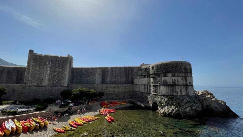 Stadtmauern Dubrovnik mit Blick auf Meer und viele Kajaks die am Strand liegen